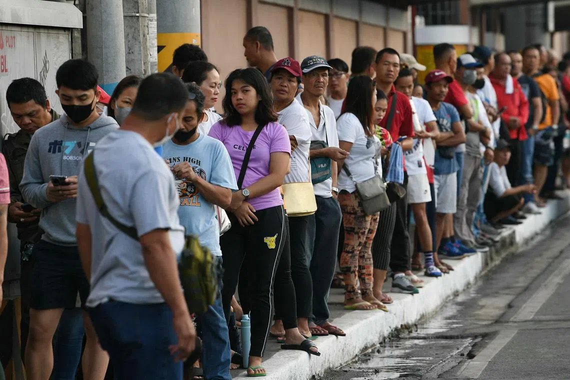Voters wait in line outside a polling station for the nationwide village  elections in Manila on Oct 30, 2023. 