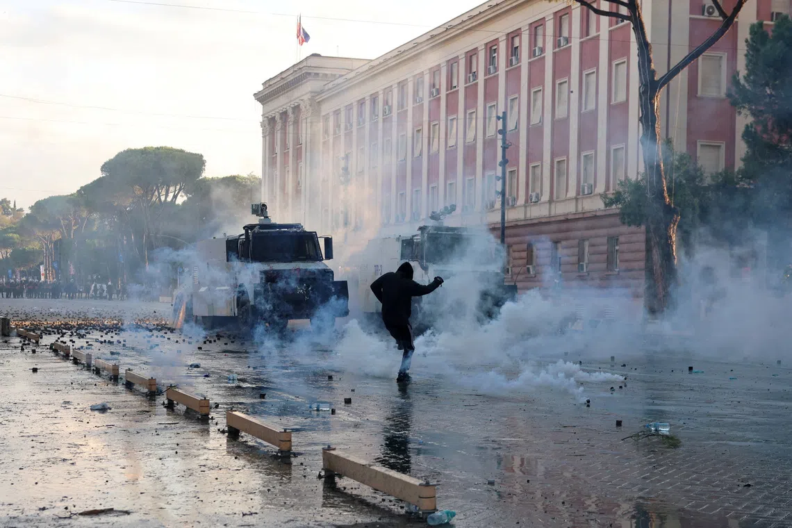 A demonstrator reacts to tear gas near police forces guarding next to the parliament building amid an anti-government protest by students in Tirana, Albania, October 16, 2026. REUTERS/Louisa Gouliamaki