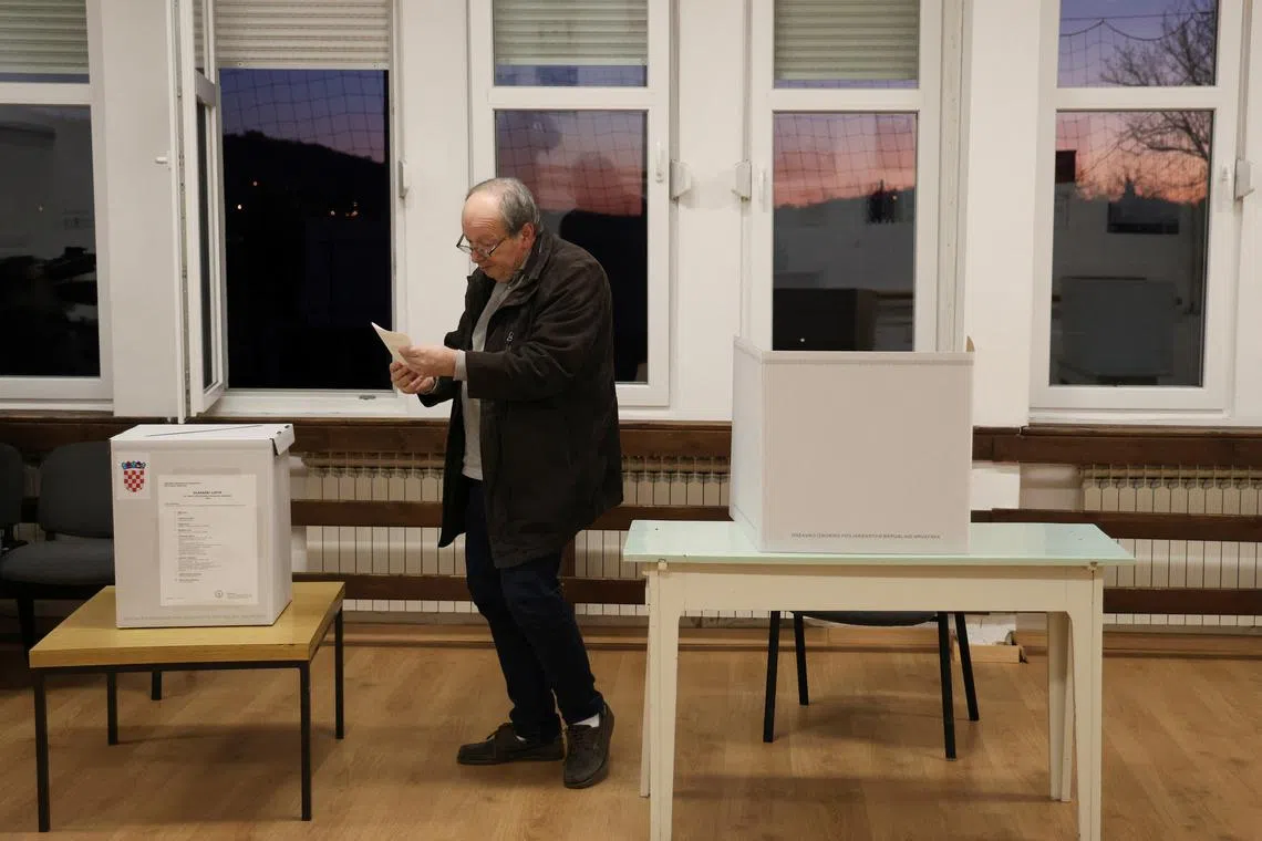 A man votes at a polling station during the presidential election in Zagreb, Croatia, December 29, 2024. REUTERS/Djordje Kojadinovic