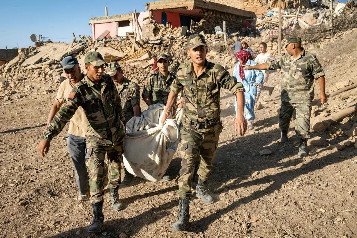 Moroccan Royal Armed Forces remove a body from the remains of a house destroyed by the quake, in the mountain village of Tafeghaghte.