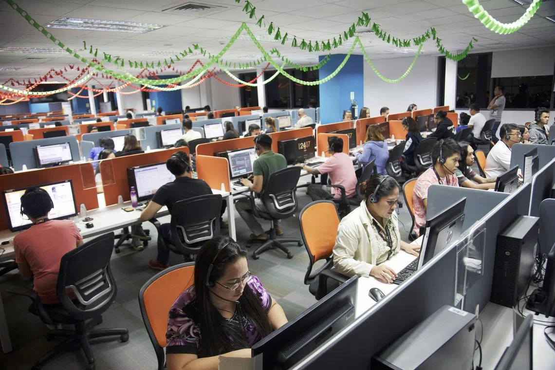 Employees wear headsets while working at desks at the 24/7 Customer Philippines Inc. call center in Cebu, Philippines, in September.  