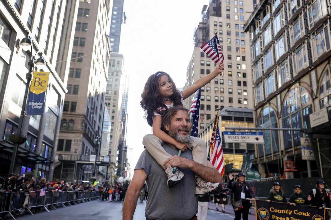 A child riding piggyback holding a US flag during the annual Veteran's Day Parade in New York City, US, Nov 11, 2024. 