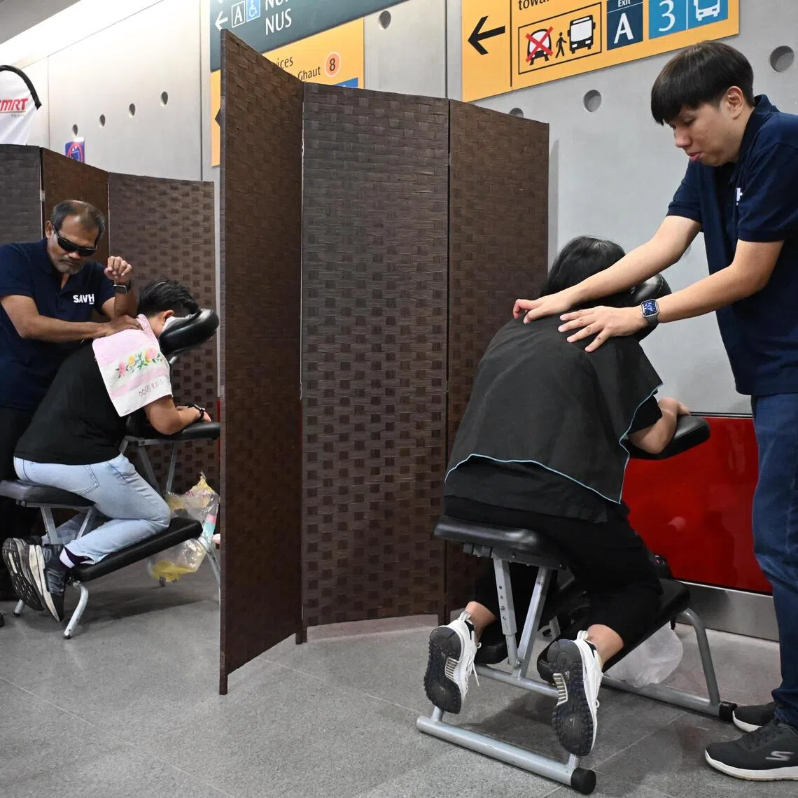 Three reflexologists from the Singapore Association of the Visually Handicapped providing complimentary reflexology to commuters.