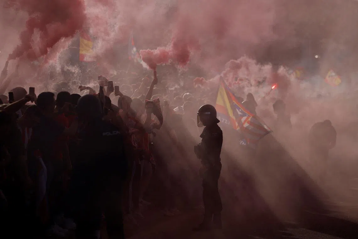 Atletico Madrid fans with flares and police during the quarter final soccer match between Atletico Madrid v Borussia Dortmund in Madrid, Spain, on April 10, 2024 