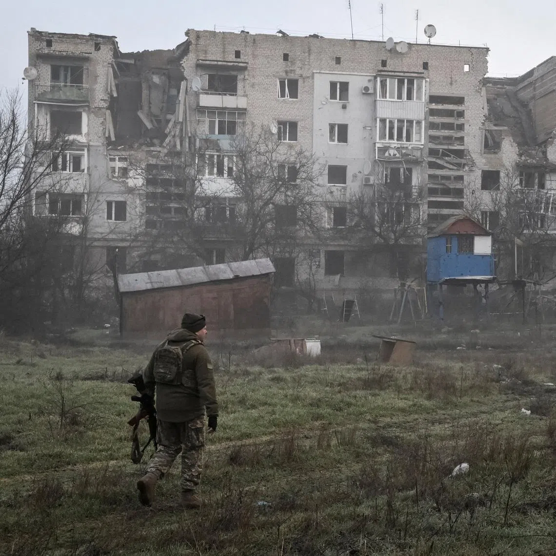 A Ukrainian service member walks near residential buildings damaged by Russian military strikes, amid Russia's attack on Ukraine, in the frontline town Orikhiv in Zaporizhzhia region, Ukraine March 26, 2026.