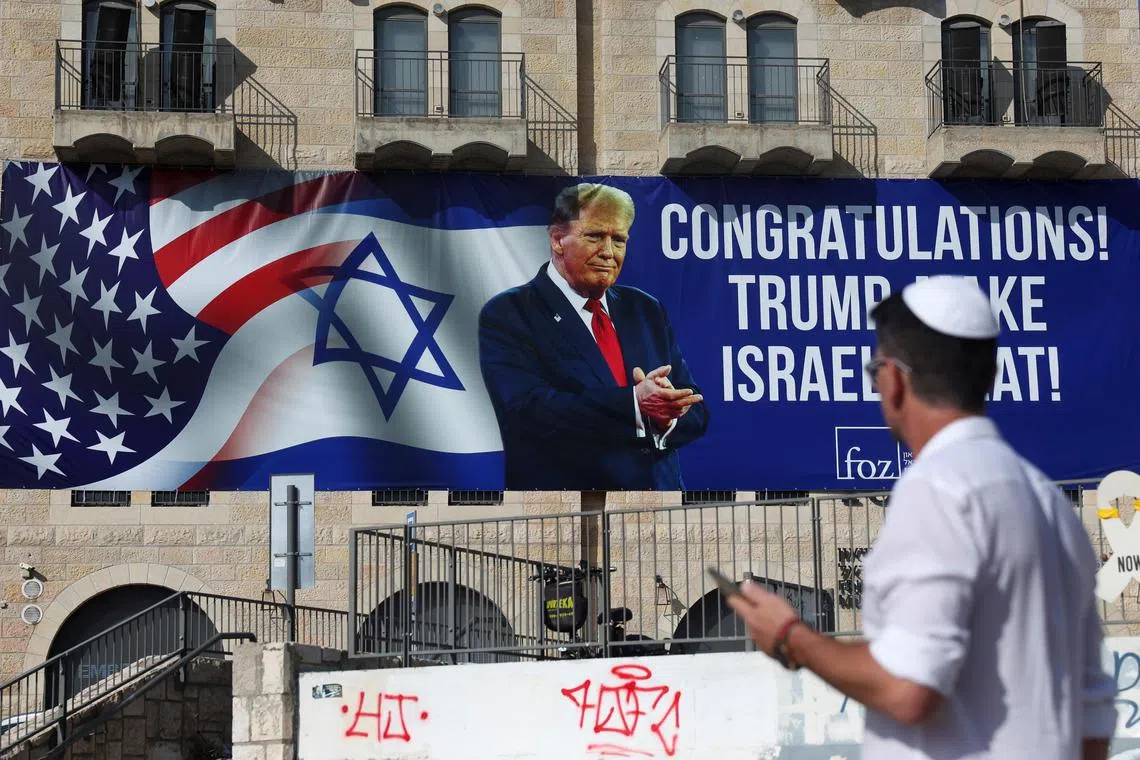A person walks near a congratulatory billboard for U.S. President-elect Donald Trump, following the 2024 U.S Presidential Election, in Jerusalem, November 7, 2024. REUTERS/Ronen Zvulun