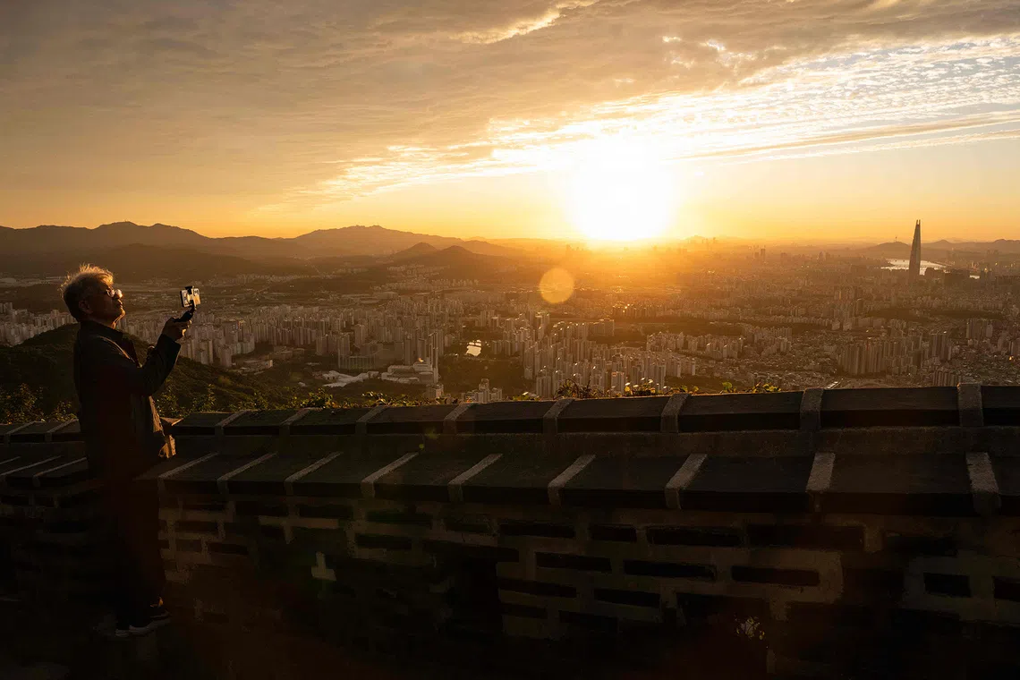 People take pictures of the city skyline from the top of Namhansanseong Seomun Observatory in Seoul on September 10, 2026. (Photo by Lillian SUWANRUMPHA / AFP)