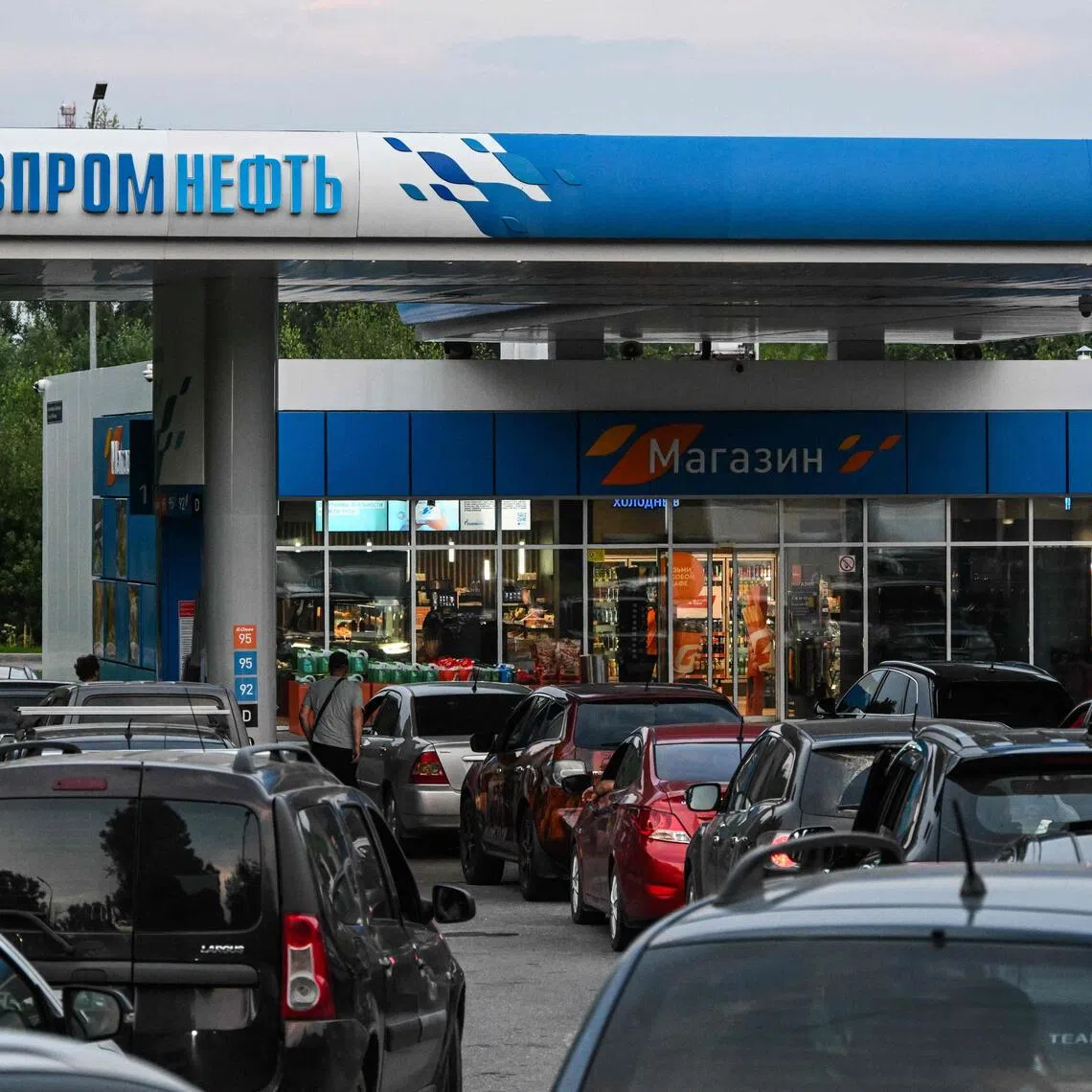 People queue to refuel their cars at a petrol station in Russia, with some gas stations and chains having sold out or closed due to a lack of supplies.