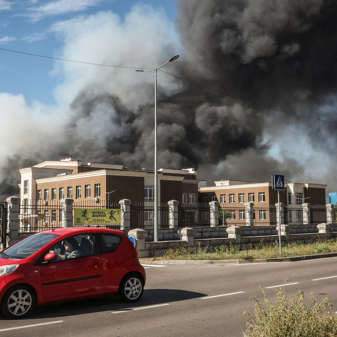 A car passes by a site of a Russian drone strike as smoke rises, amid Russia’s attack on Ukraine, in Kyiv region, Ukraine, on Aug 29.