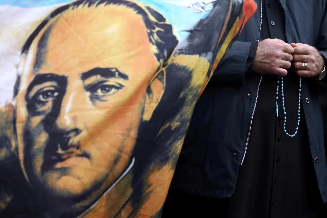 FILE PHOTO: A priest holds a rosary next to a flag with the portrait of late Spanish dictator Francisco Franco outside Mingorrubio-El Pardo cemetery, in Madrid, Spain, October 24, 2019. REUTERS/Sergio Perez/File Photo
