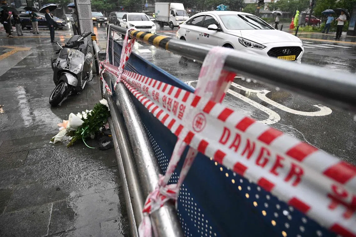 Flowers (bottom L) are placed at the site of a car accident, which left at least nine people dead, in Seoul on July 2, 2024. At least nine people were killed and four others were injured when a car struck pedestrians near Seoul city hall on July 1, police said. (Photo by Jung Yeon-je / AFP)