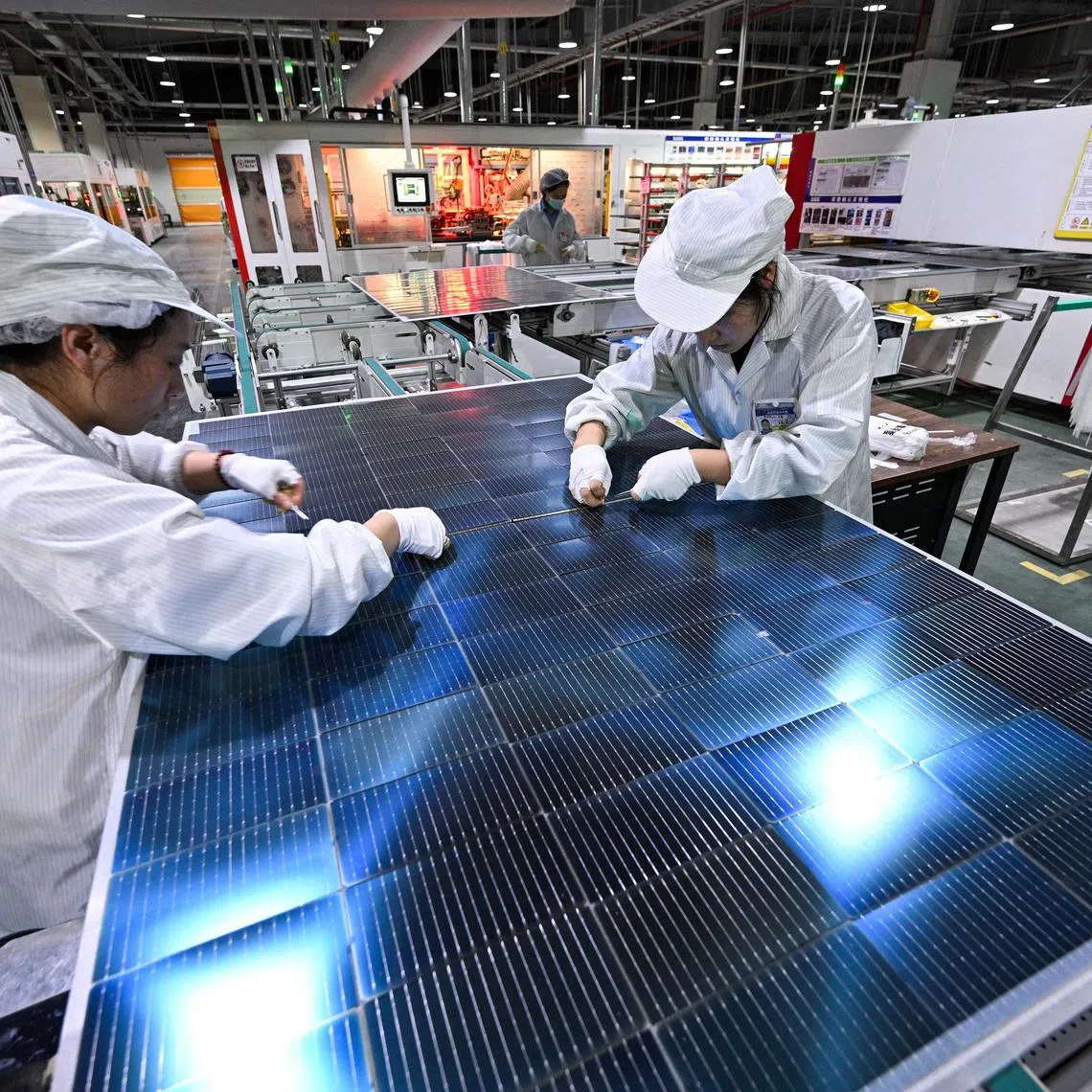 Workers producing photovoltaic modules for solar panels in a factory in Suqian, east China's Jiangsu province. 