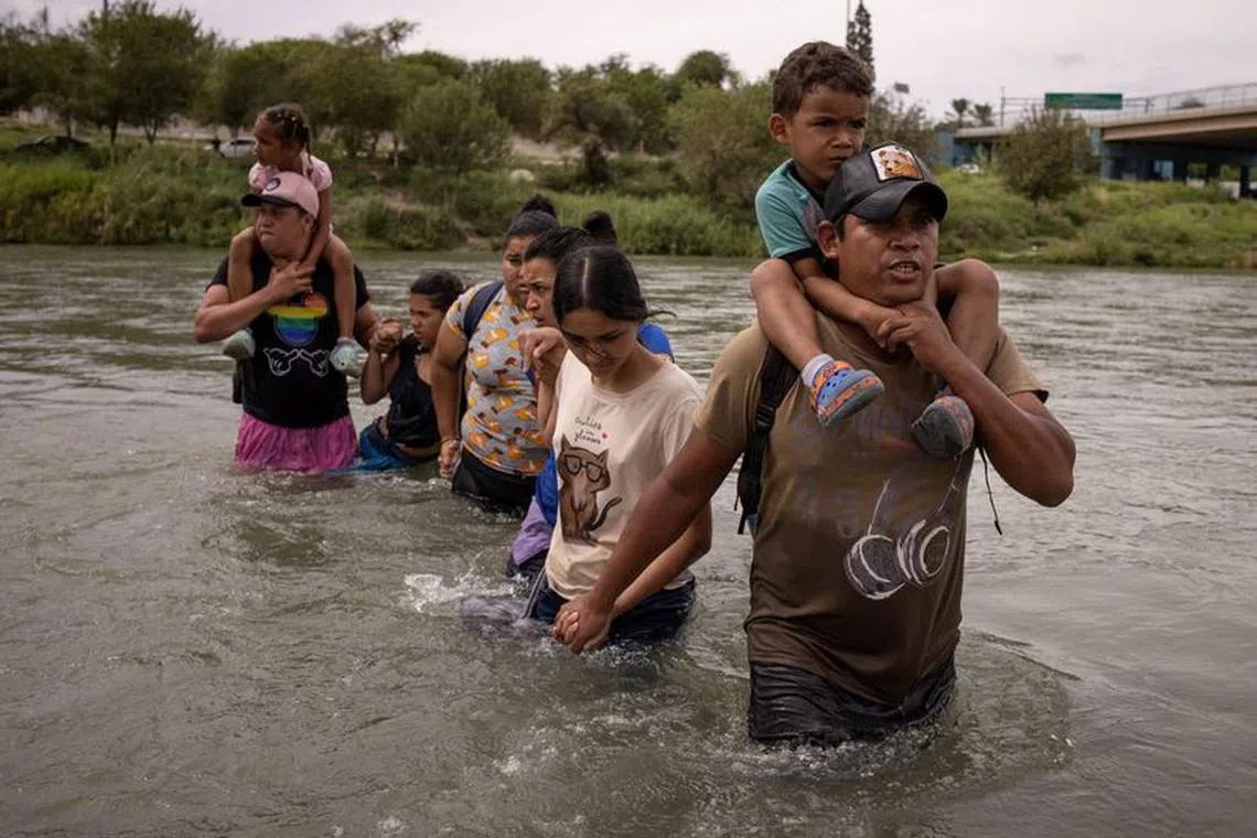 FILE PHOTO: Orlando, a migrant from Ecuador, carries four-year-old compatriot, Peter, as they wade through the Rio Grande river from Mexico into Eagle Pass, Texas, U.S. October 6, 2023. REUTERS/Adrees Latif/File Photo