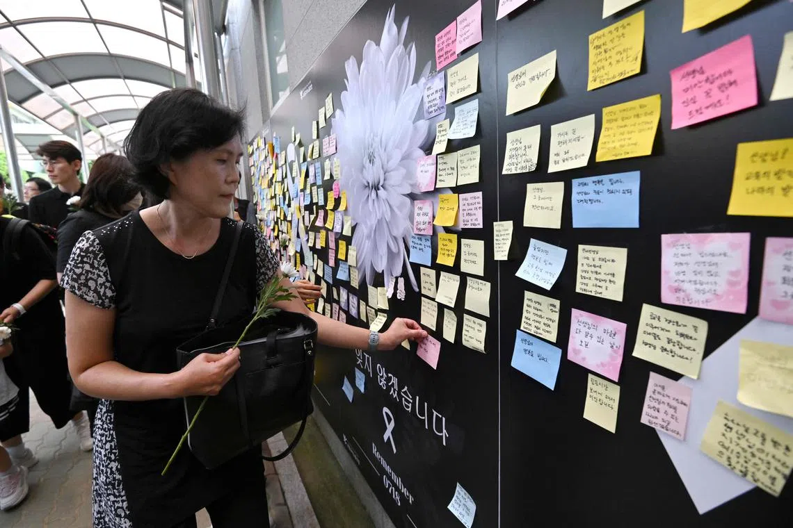 A mourner attaching a message on a memorial wall for an elementary school teacher who died in an apparent suicide in July, at Seoul Seoi Elementary School.