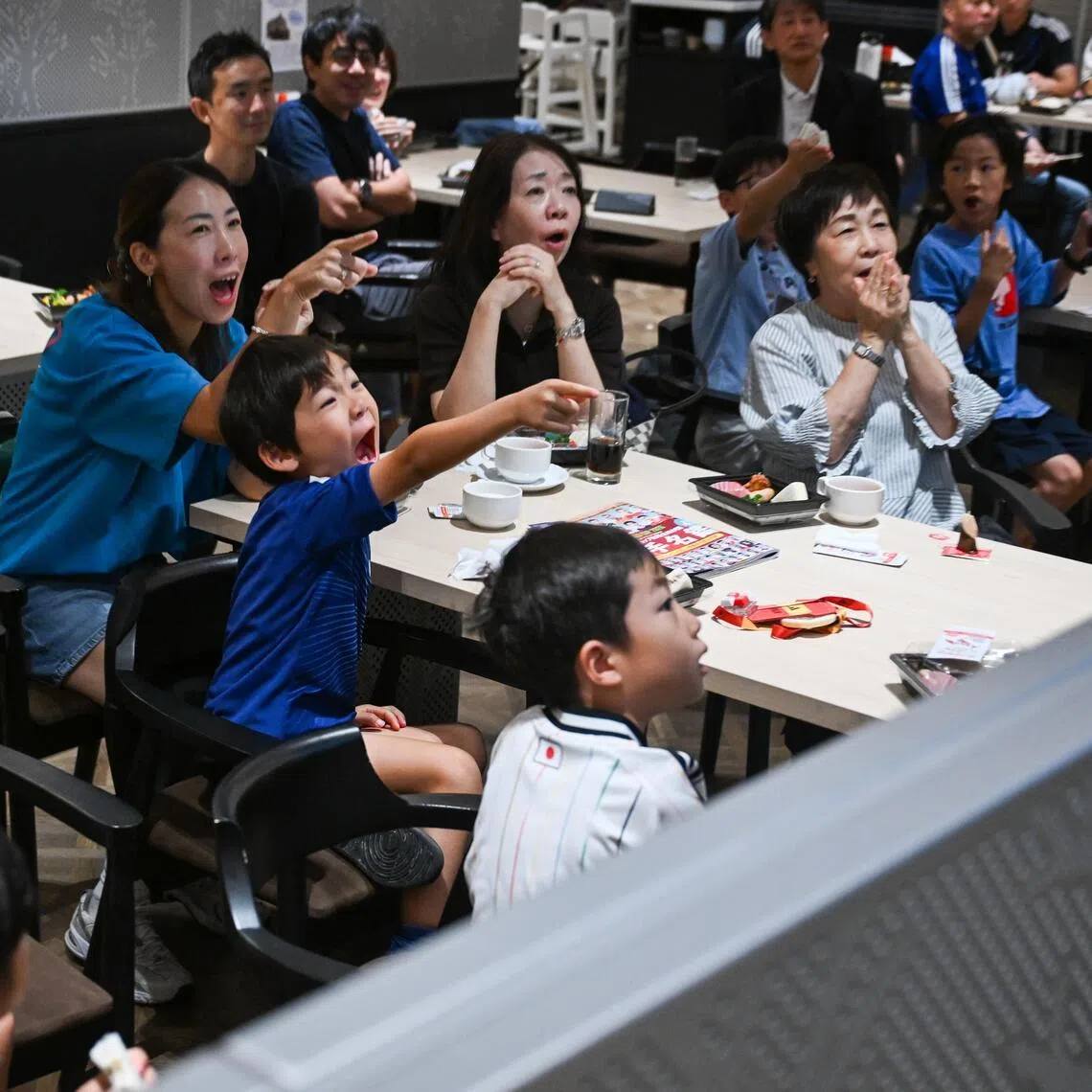 Hiroto Arafuka (middle, in blue) and his mother Masumi cheering for Japan during the team’s 1-1 World Cup draw with Sweden on June 26.