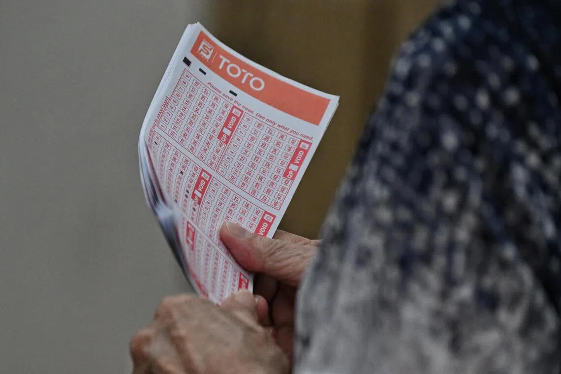 A woman holds her tickets while queueing on the last day to place bets for the Toto Hong Bao Draw, at the Singapore Pool's Outlet at Toa Payoh HDB Centre on Feb 3, 2023.