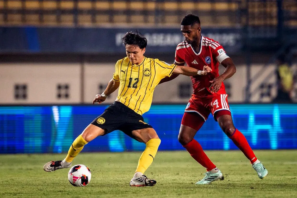 Singapore captain Hariss Harun (right) tussling with Stuart Wilkin during the Lions’ 6-0 FIFA ASEAN Cup loss to Malaysia at the Si Jalak Harupat Stadium in Bandung on Oct 1.