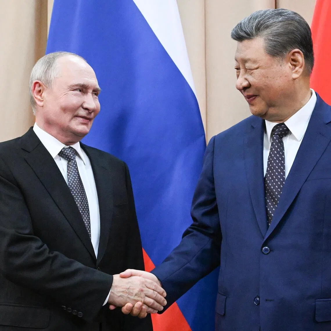 Russian President Vladimir Putin (left) and Chinese President Xi Jinping shake hands as they pose for photos ahead of a summit in Kyrgyzstan.