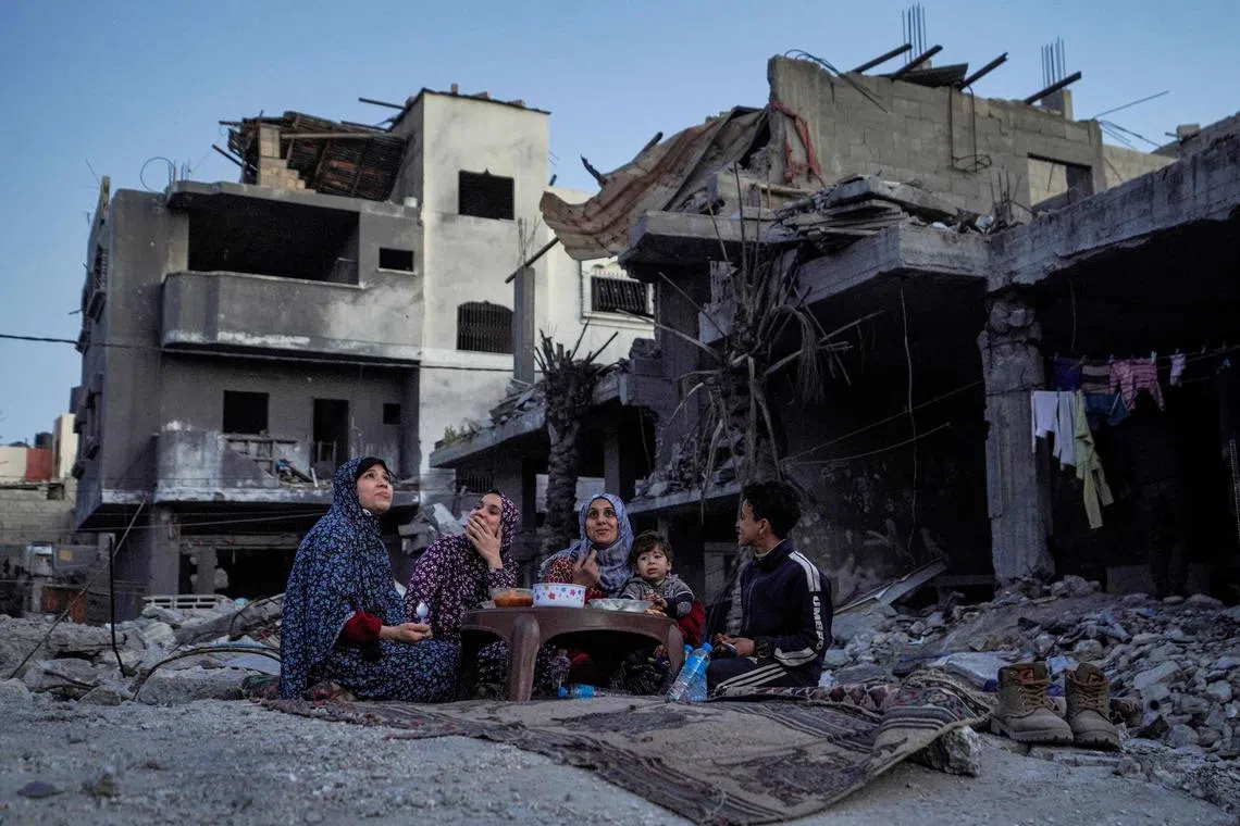 The Palestinian Al-Naji family eating an iftar meal, the breaking of fast, amidst the ruins of their family house, on the first day of the Muslim holy fasting month of Ramadan, in Deir el-Balah in the central Gaza Strip on Mar 11, 2024.