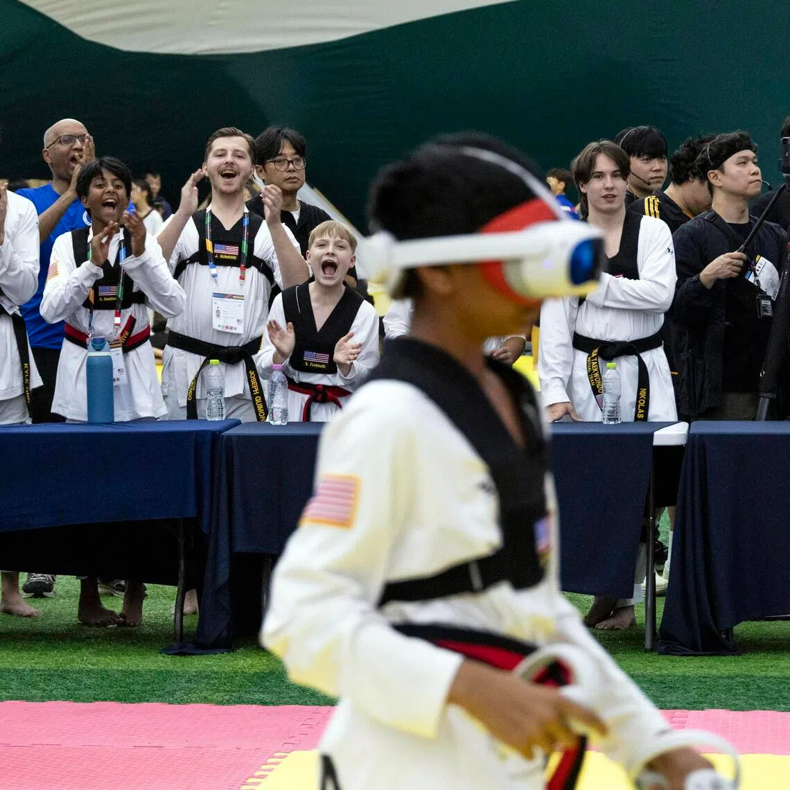 The US team cheering on their teammates during a virtual taekwondo bout at the Chuncheon Korea Open International Taekwondo Championships in South Korea on July 18, 2026. The contactless version of the Korean martial art is making its debut at the Sept 19-Oct 4 Asian Games. Critics say it is a glorified video game.
