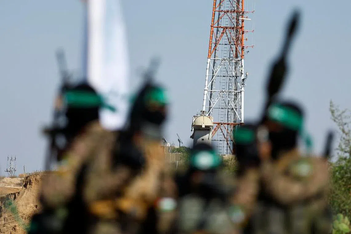 Palestinian fighters from the armed wing of Hamas take part in a military parade in front of an Israeli military site to mark the anniversary of the 2014 war with Israel, near the border in the central Gaza Strip, July 19, 2023. REUTERS/Ibraheem Abu Mustafa/File Photo