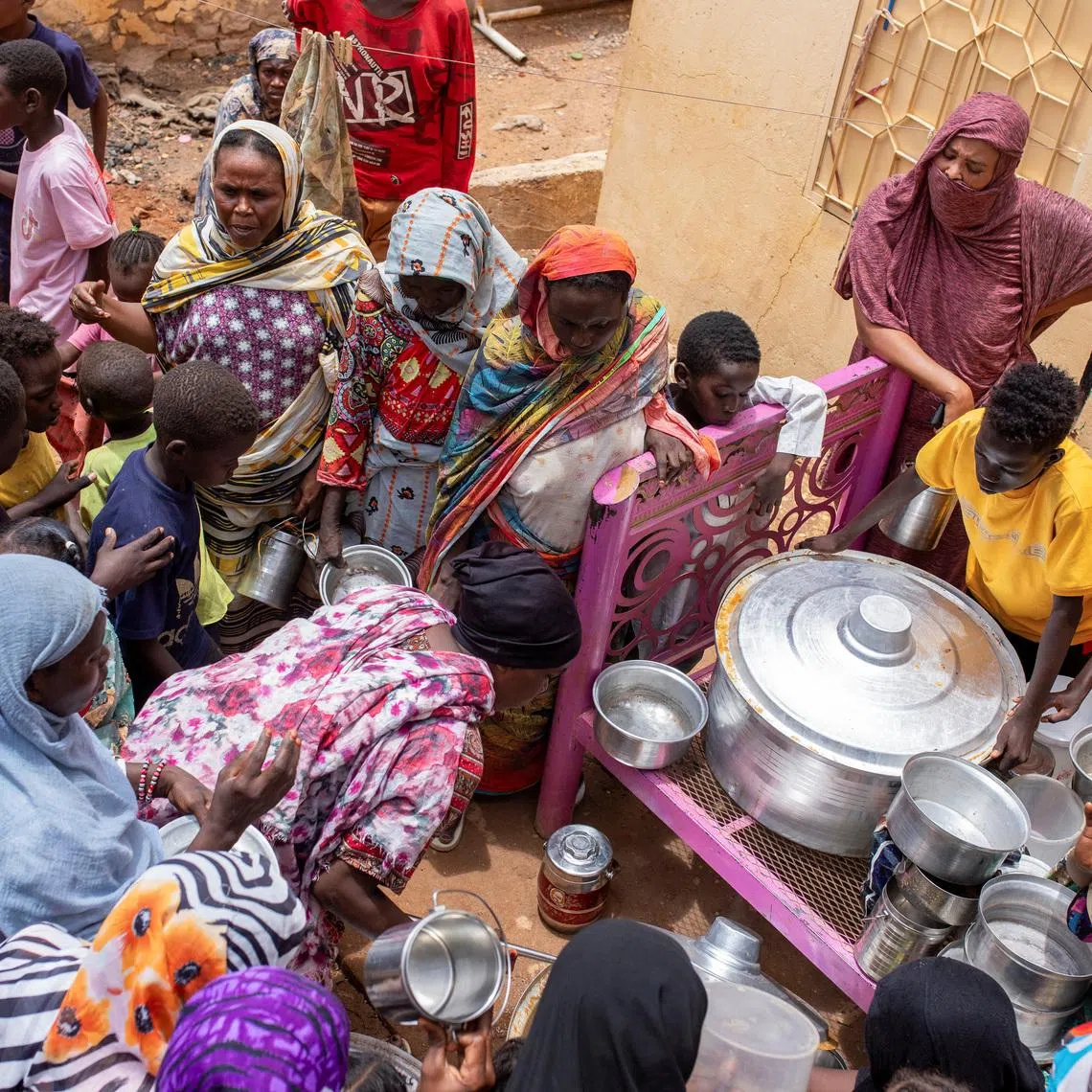 Sudanese women from community kitchens run by local volunteers distribute meals for people who are affected by conflict and extreme hunger and are out of reach of international aid efforts, in Omdurman, Sudan, July 27, 2024. REUTERS/Mazin Alrasheed