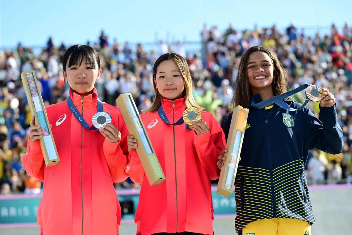 Paris 2024 Olympics - Skateboarding - Women's Street Victory Ceremony - La Concorde 3, Paris, France - July 28, 2024. Gold medallist Coco Yoshizawa of Japan celebrates on the podium with silver medallist Liz Akama of Japan and bronze medallist Rayssa Leal of Brazil. REUTERS/Angelika Warmuth