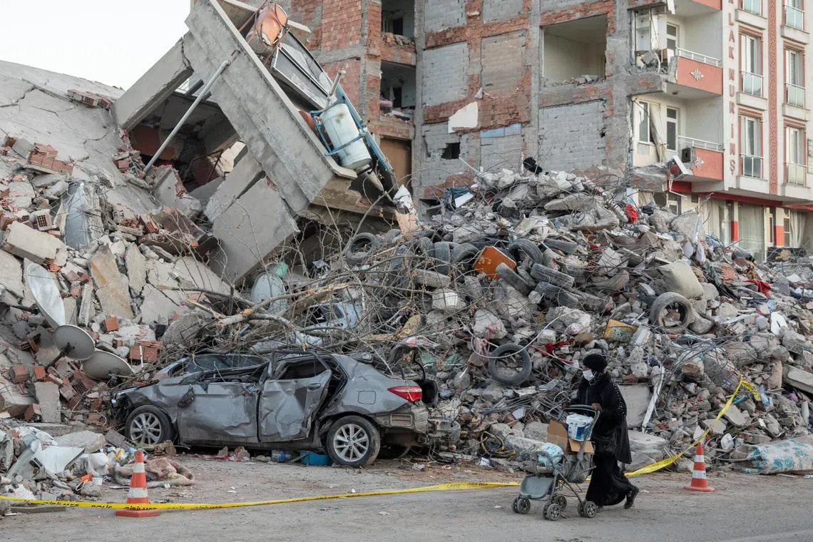 A woman wheels a stroller past destroyed properties following the deadly earthquake in Kahramanmaras, Turkey, on Feb 16.