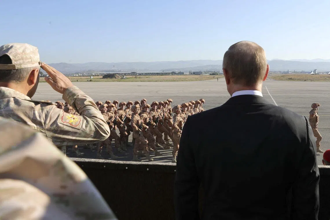 FILE PHOTO: Russian President Vladimir Putin (R) and then Defence Minister Sergei Shoigu watch servicemen passing by as they visit the Hmeymim air base in Latakia Province, Syria December 11, 2017. Sputnik/Mikhail Klimentyev/Sputnik via REUTERS/File Photo