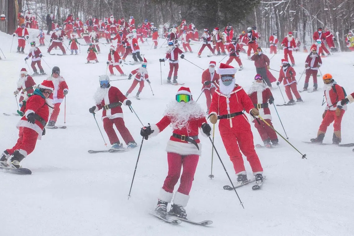 People dressed in Santa Claus costumes ski down South Ridge at Sunday River resort in Newry Maine, on Sunday, December 14, 2025, to raise money for The River Fund and the Boyne Forever Foundation. (Photo by Lauren OWENS LAMBERT / AFP)
