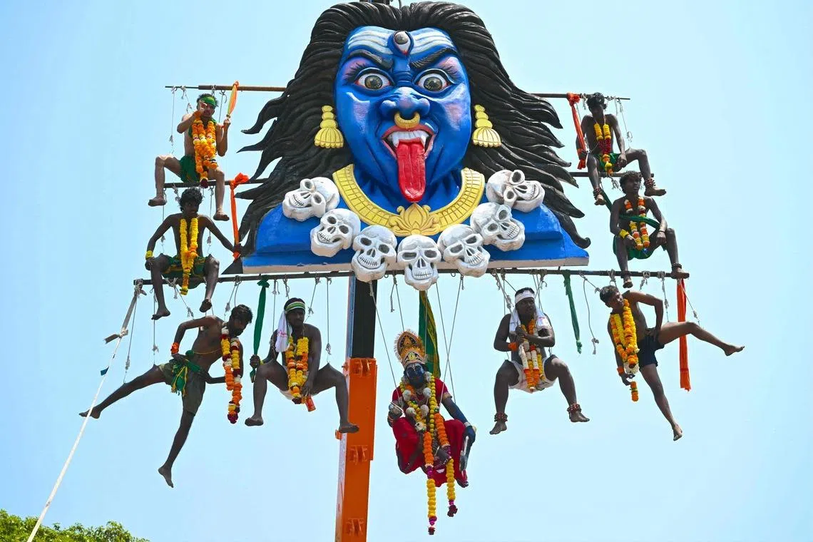 Tamil devotees suspended in air from a crane by piercing themselves onto metal hooks to honour the Hindu God Murugan during Panguni Uthiram festival in Mumbai on April 1, 2026. 