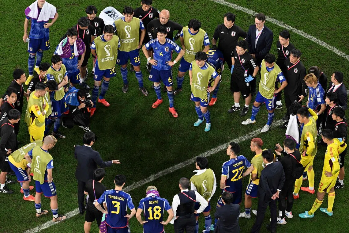 Japan's coach Hajime Moriyasu (Left, bottom) talks to the players after losing in the penalty shoot-out after extra time at the Qatar 2022 World Cup round of 16 football match between Japan and Croatia.