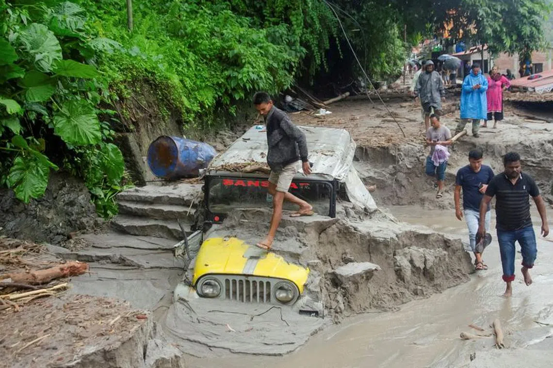 FILE PHOTO: People walk along a street as a jeep is buried in the mud due to the flood at Teesta Bazaar in Kalimpong District, West Bengal, India October 4, 2023. REUTERS/Brihat Rai/File Photo