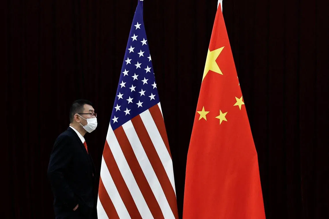 FILE PHOTO: A man walks past the national flags of China and the U.S. before a meeting between China's Vice Premier He Lifeng and U.S. Treasury Secretary Janet Yellen at the Guangdong Zhudao Guest House, in Guangzhou, Guangdong province, China, April 6, 2024. REUTERS/Tingshu Wang/File Photo