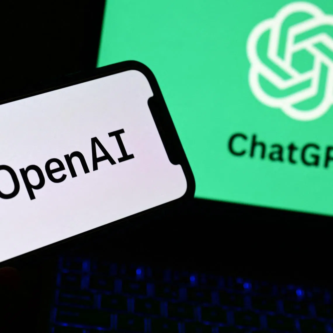 A photo taken on October 4, 2023 in Manta, near Turin, shows a smartphone and a laptop displaying the logos of the artificial intelligence OpenAI research laboratory and ChatGPT robot. (Photo by MARCO BERTORELLO / AFP)