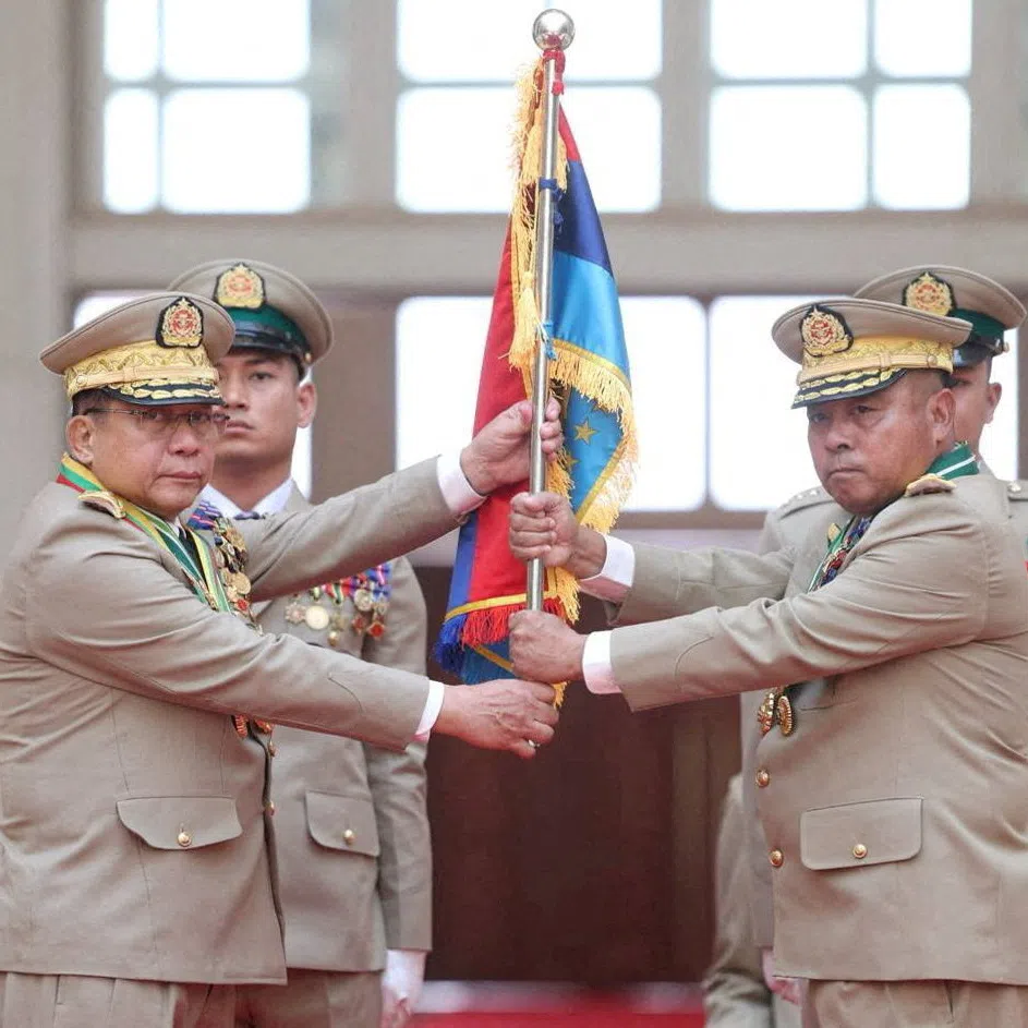 Myanmar President Min Aung Hlaing (left) hands over a flag to military chief General Ye Win Oo.