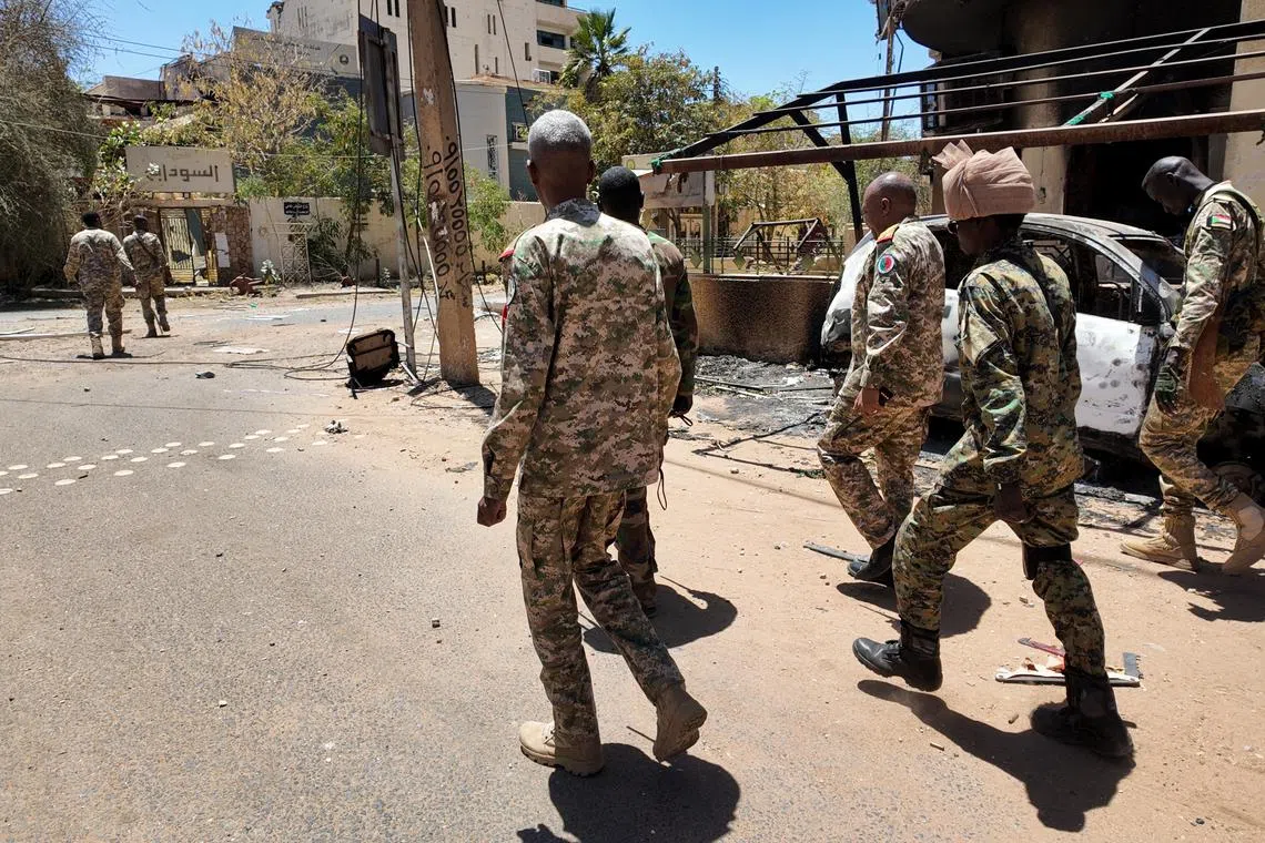 FILE PHOTO: Members of the Sudanese army walk next to destroyed military vehicles after a battle with Rapid Support Forces (RSF) in the capital Khartoum, Sudan March 25, 2025. REUTERS/Stringer/File Photo