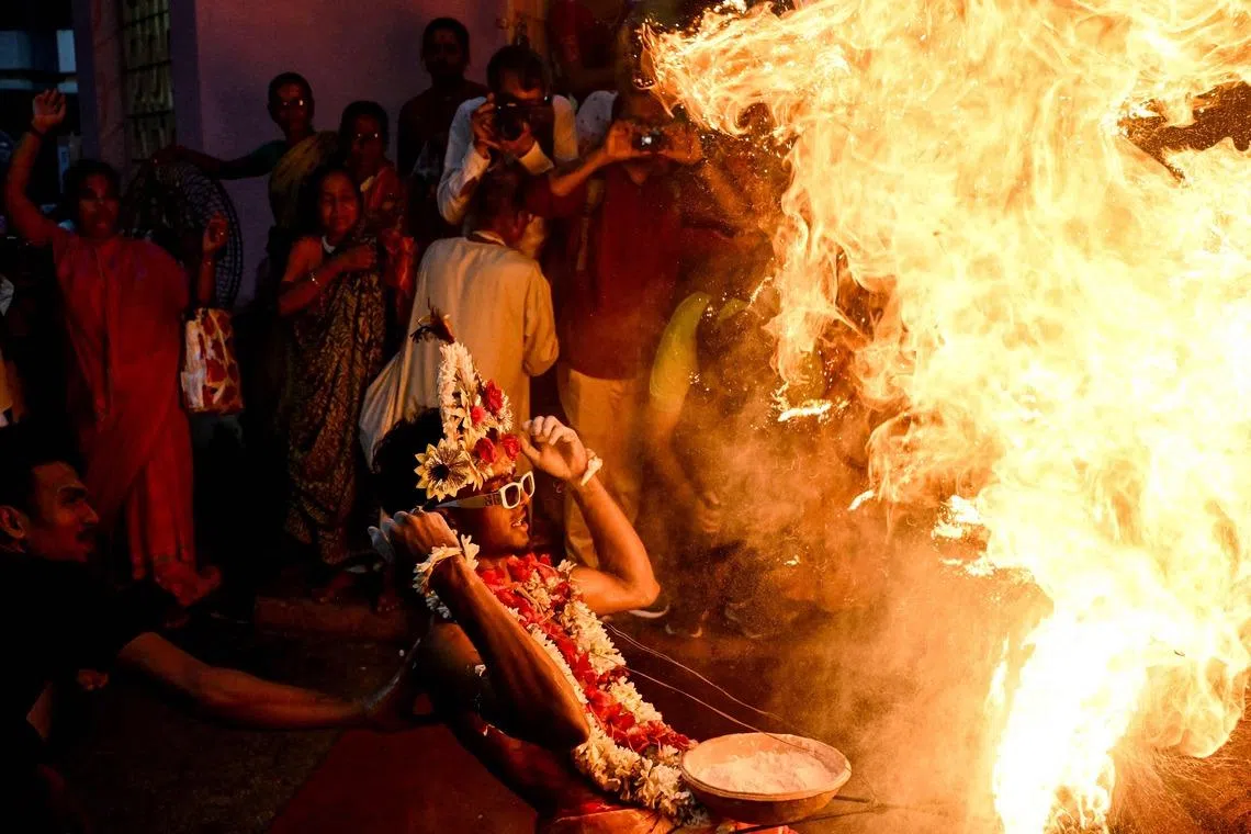 TOPSHOT - Hindu devotees ignite flammable holy powder as they perform rituals to celebrate Gajan Festival in Kolkata on April 13, 2026. (Photo by Dibyangshu SARKAR / AFP)