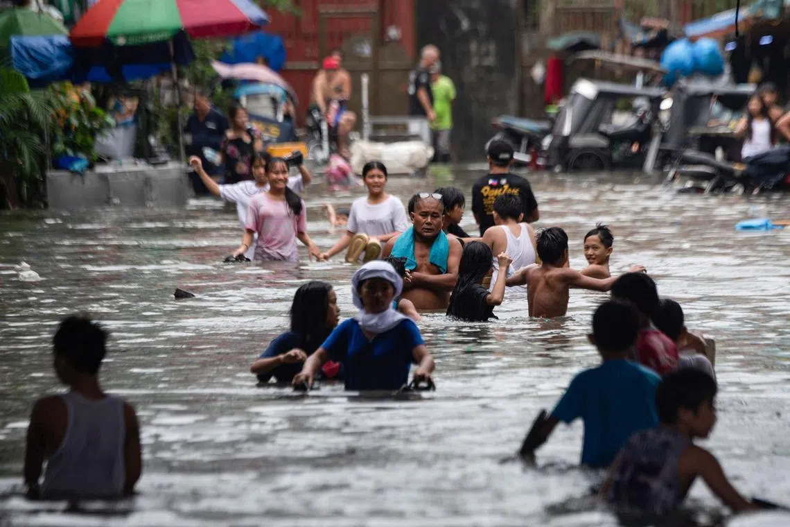 People wade through a flooded street in Manila, on July 21.