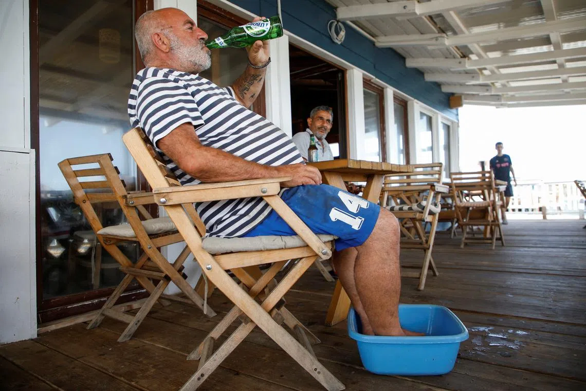 A man refreshes himself with beer during the first summer heatwave this year in Barbana near Ulcinj, Montenegro, June 19, 2024. REUTERS/Stevo Vasiljevic