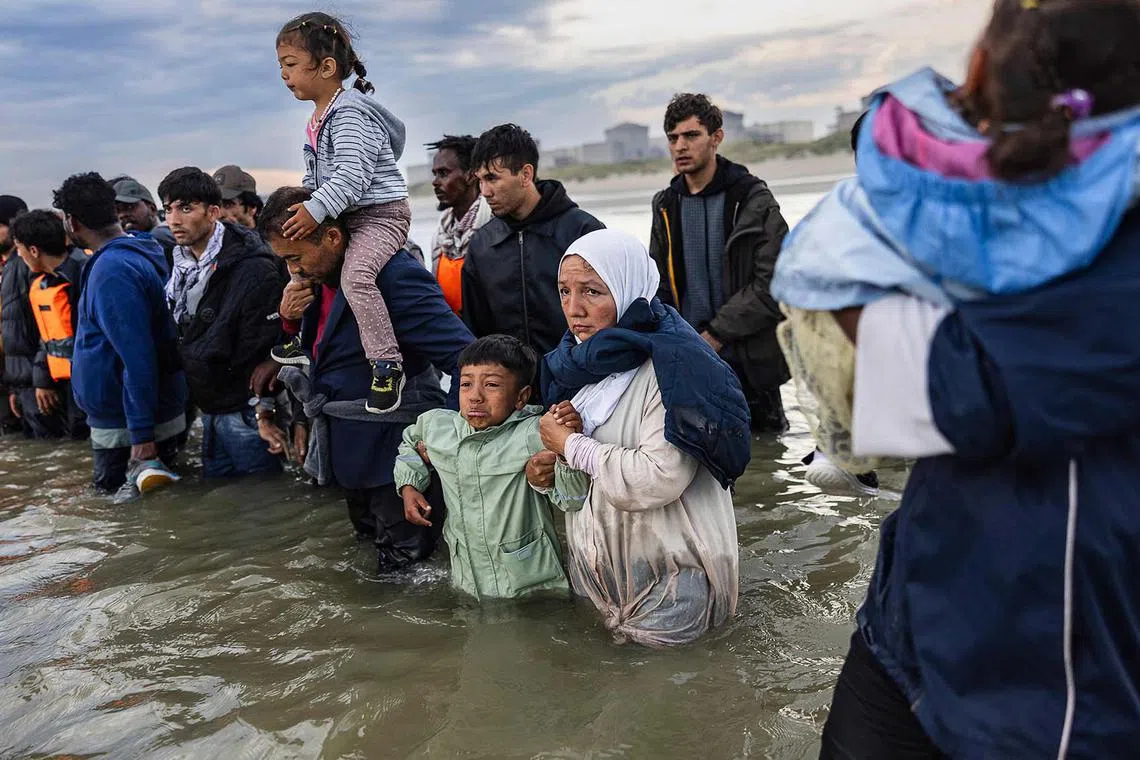 TOPSHOT - A child cries as migrants try to board a smuggler's boat in an attempt to cross the English Channel off the beach of Gravelines, northern France on August 12, 2025. (Photo by Sameer Al-DOUMY / AFP)