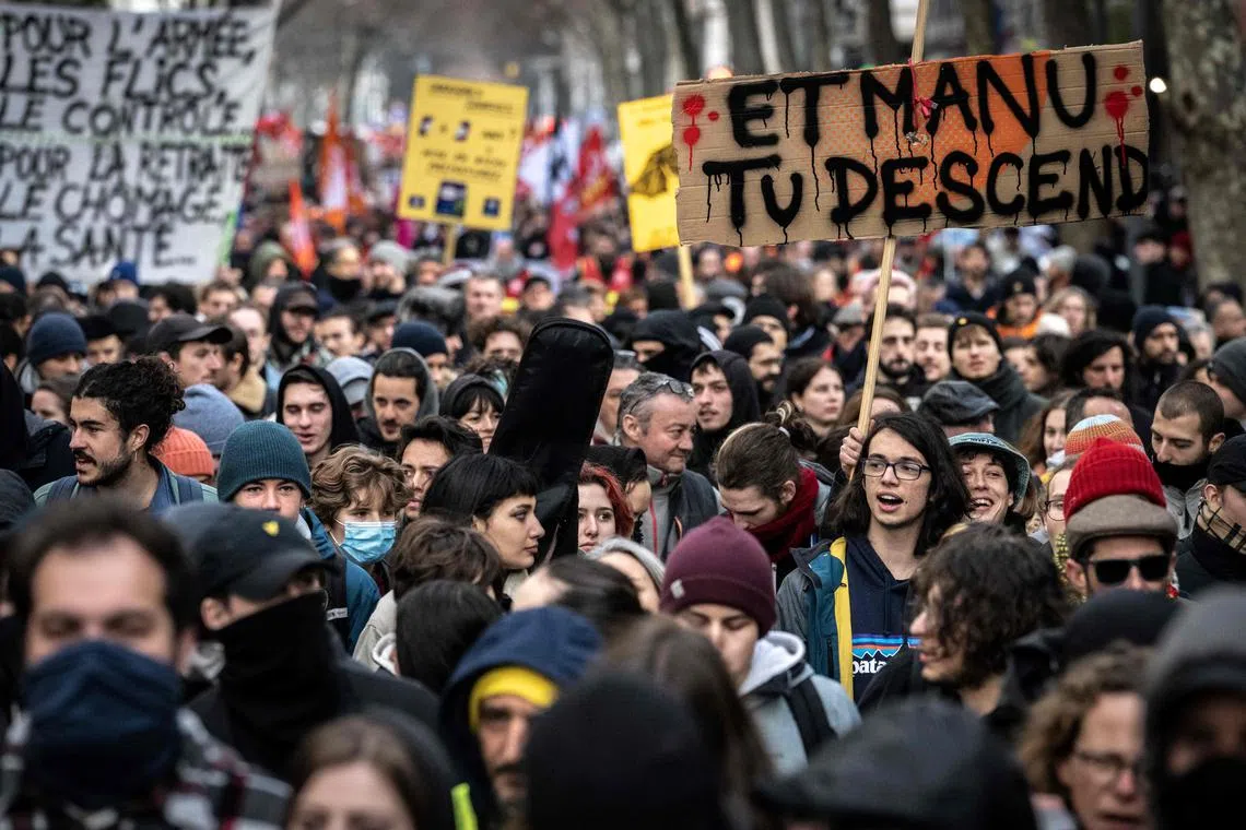 A protester holds a placard reading "Manu (French President Emmanuel Macron) get down here !" amid a day of nationwide strikes in France over planned pension reforms.