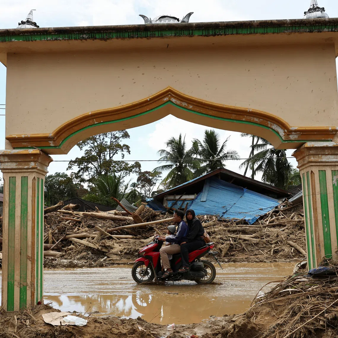 Local residents ride a motorbike at an area following deadly flash flood in Batang Toru, South Tapanuli, North Sumatra province, Indonesia, December 6, 2025. REUTERS/Willy Kurniawan