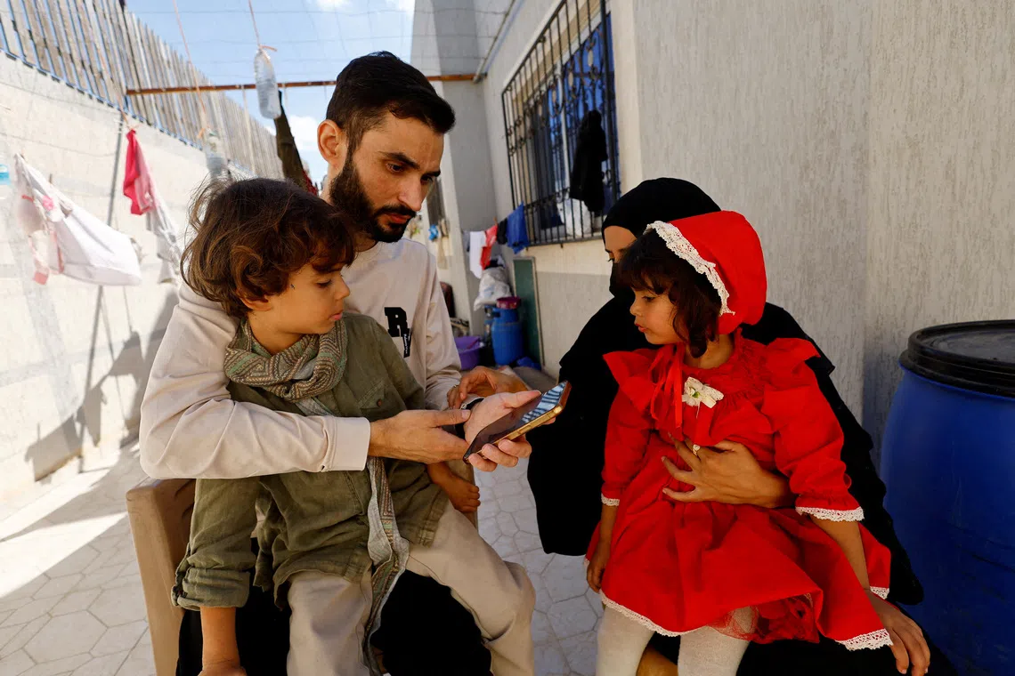 Freed Palestinian detainee Shadi Abu Sido sits with his wife Hanaa Bahlul and their children at their home in Nuseirat, central Gaza Strip, after he was released from Israeli detention as part of a ceasefire deal between Hamas and Israel, October 14, 2025. REUTERS/Mahmoud Issa