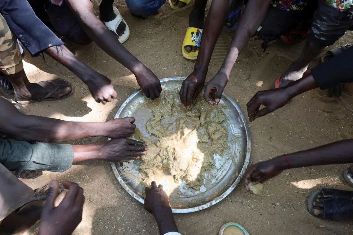 FILE PHOTO: Refugees eat food in the Adre Sudanese refugee camp in Adre, Chad, November 8, 2023. REUTERS/El Tayeb Siddig/File Photo