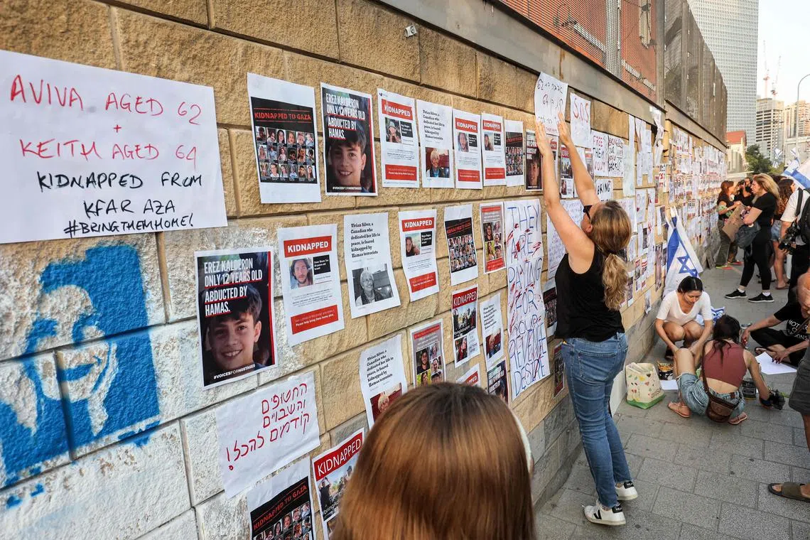 Supporters and family members of Israeli hostages snatched by the Palestinian militant group Hamas put up signs seeking information on their whereabouts, in central Tel Aviv.