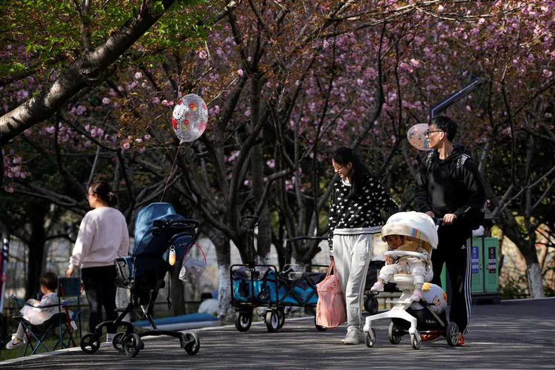FILE PHOTO-A parents pushes a stroller with a baby in a park in Shanghai, China, April 2, 2023. REUTERS/Aly Song/File Photo
