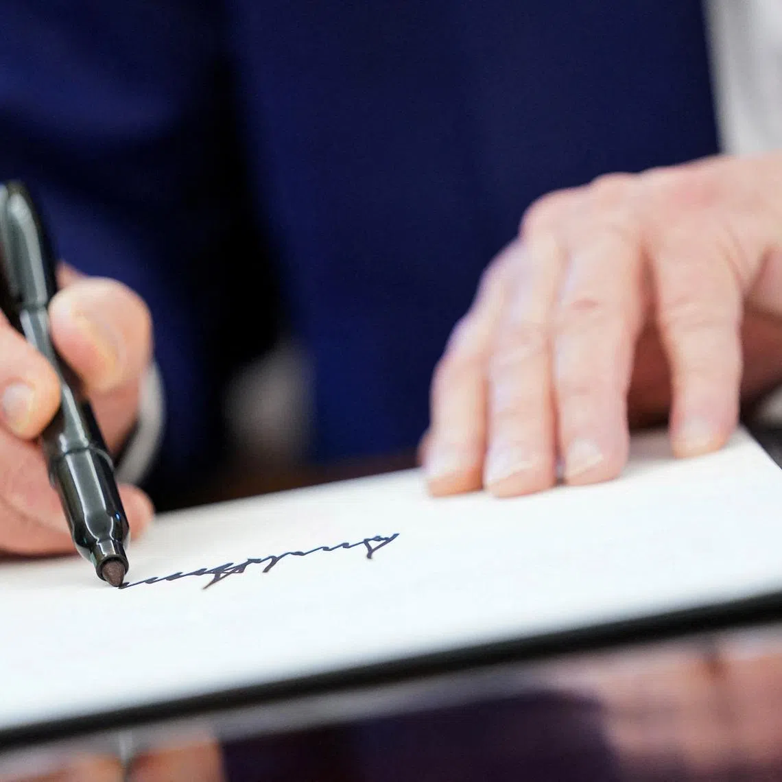 FILE PHOTO: U.S. President Donald Trump writes his signature, as he signs executive orders and proclamations in the Oval Office at the White House in Washington, D.C., U.S., April 9, 2025. REUTERS/Nathan Howard/File Photo
