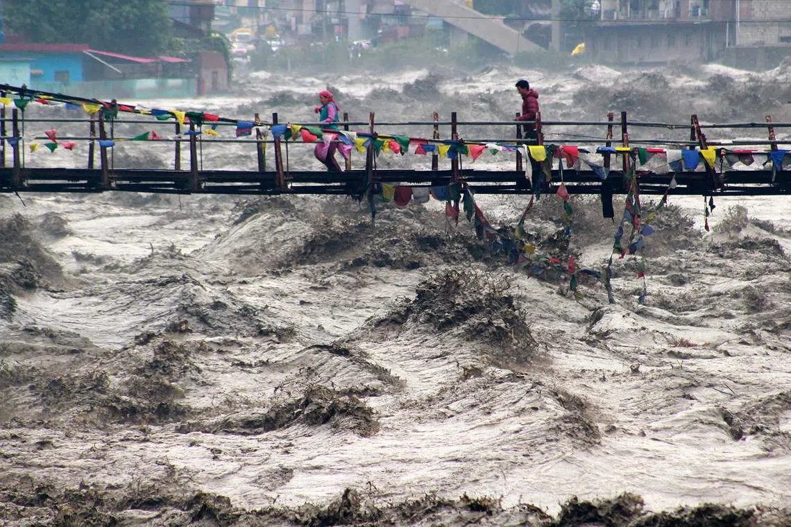 People walking on a bridge to cross the overflowing Beas River following heavy rain in Kullu district in the northern state of Himachal Pradesh, India, Aug 26, 2025. 