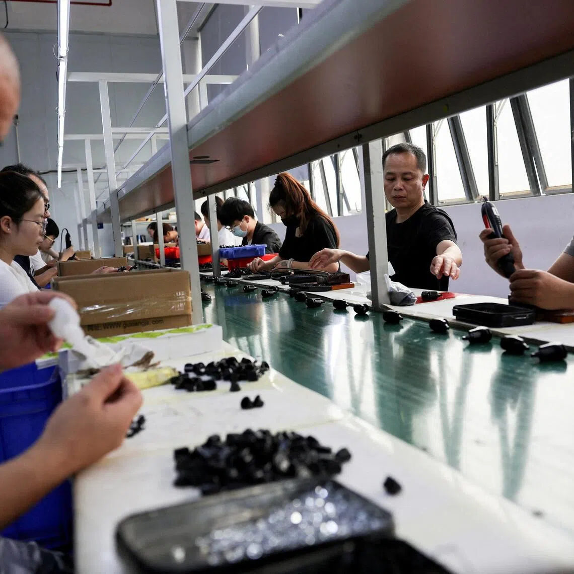 Employees work at an assembly line producing car smartphone holders at a plastic accessories factory in Dongguan, China, on April 2.